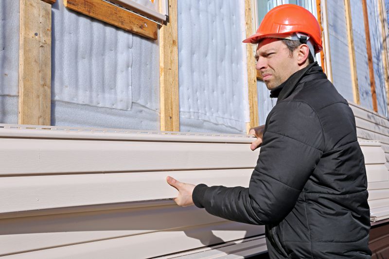 Professional installing vinyl siding on a residential home